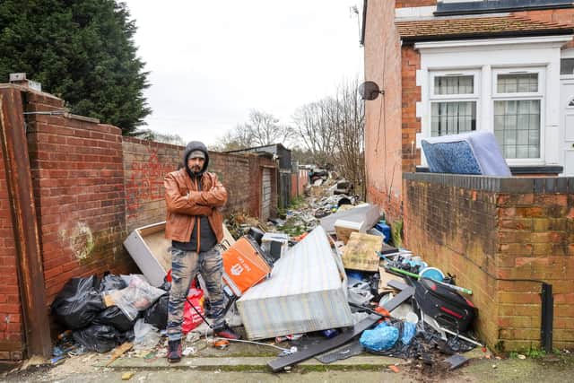 Raj Chonk standing next to fly-tipping pile at the rear of Slade Road in Stockland Green, Birmingham.