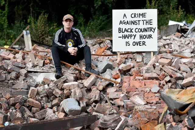 A distraught campaigner sits amid the ruins of The Crooked House following demolition