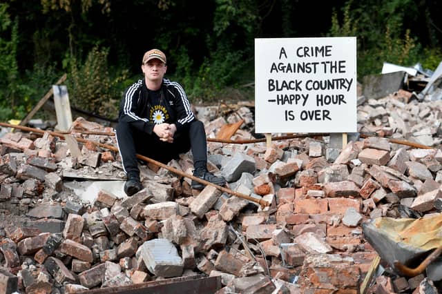 A distraught campaigner sits amid the ruins of The Crooked House following demolition