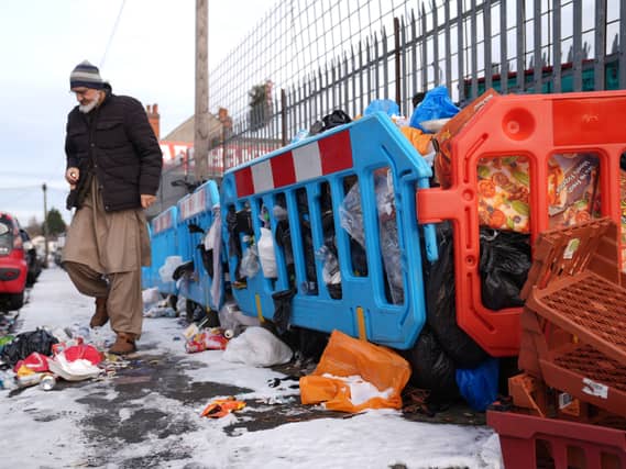 A person walks among piles of uncollected refuse bags and household waste in the Saltley area of Birmingham (Joe Giddens/PA)