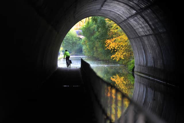 A cyclist makes his way through the tunnel along the Main Line Canal, Smethwick, as the autumn colours reflect in the water