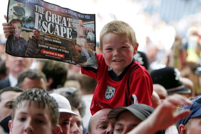 A young Albion fan with an Albion 'Great Escape' Express & Star supplement celebrates amid the sea of bodies on the pitch at full-time. Pic: Getty