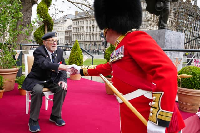 Second World War veteran Alan Kennett shakes hands with a member of the Band of the Irish Guards, near Parliament Square, central London, ahead of a military procession. Credit: Jeff Moore/PA Wire