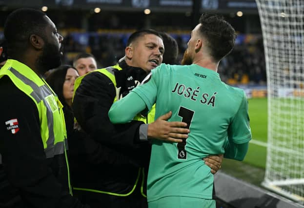 Stewards usher Wolverhampton Wanderers' Portuguese goalkeeper Jose Sa back to the pitch after he remonstrated with a fan at half-time (Getty)