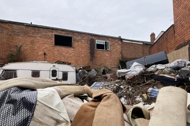 Rubbish is building up behind a disused furniture shop