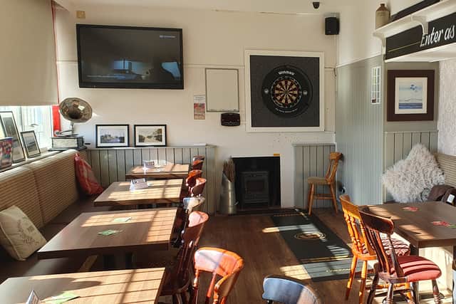 The front room is open and spacious, with a dart board on the wall