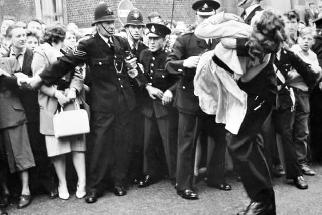 A girl is carried to safety after fainting among the massive crowds in North Street.