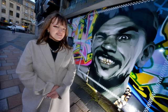 Stafford based artist and University of Wolverhampton graduate Eve Whitfield with her portrait of Goldie which has been placed in an empty shop in Queens Square