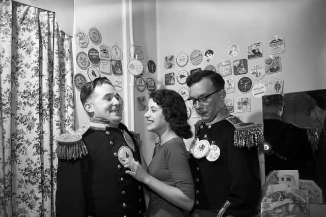 Comedians Eric Morecambe and Ernie Wise present their collection of beer mats in their dressing room at Dudley Hippodrome in Worcestershire. With them is 17-year-old Ann Harris.