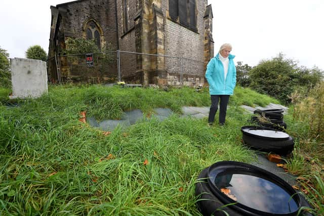 Residents near St John's Church, Dudley, are angry about the state of the cemetery..Judith Fisher next to tyres and tiles, which have been dumped on the graveyard