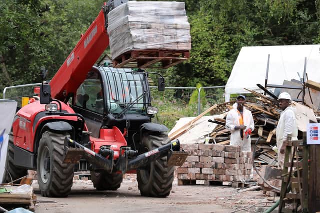 A vehicle a exits the site carrying a pallet of bricks from the demolished building