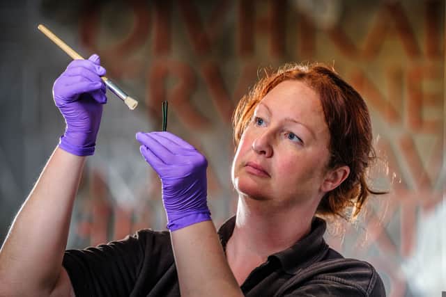 A conservationist at Wroxeter Roman City examines a pair of tweezers used to remove armpit hair from Roman men and women.