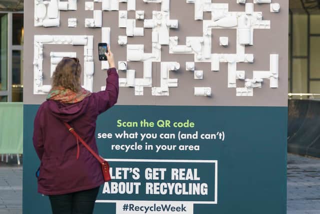 A person uses a mobile phone to scan a QR code made with recycled materials outside Birmingham New Street station. Photo: Dominic Lipinski/PA Wire