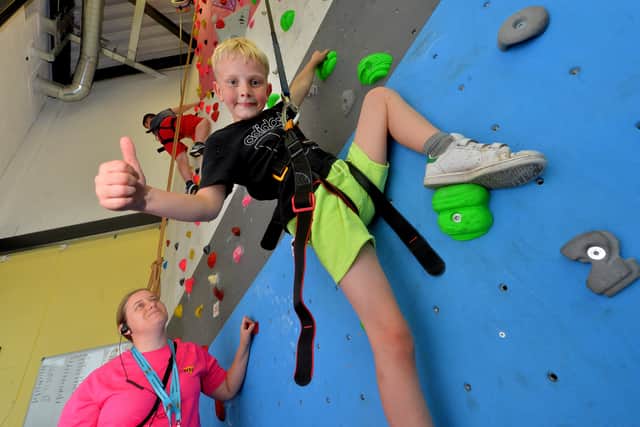 Bailey Taggart, aged nine, takes on the climbing wall watched by youth worker Anna Reece