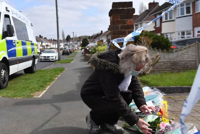 A woman puts flowers down outside the house on Boundary Avenue