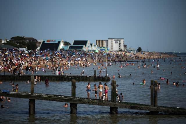 People relax on the beach and in the water in Southend-on-Sea. (Photo by HENRY NICHOLLS/AFP via Getty Images)