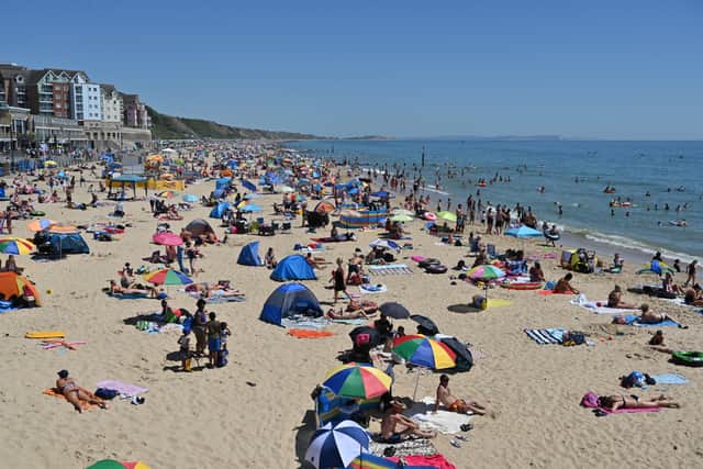Beachgoers enjoy the sunshine as they sunbathe and play in the sea on Boscombe beach in Bournemouth. (Photo by GLYN KIRK/AFP via Getty Images)