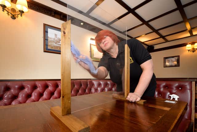 Hayley Hall, licensee and manager of the Lych Gate Tavern, cleans one of the new table screens