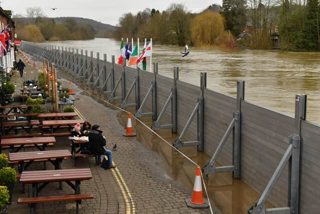 People eating by in front of temporary flood defences in Bewdley