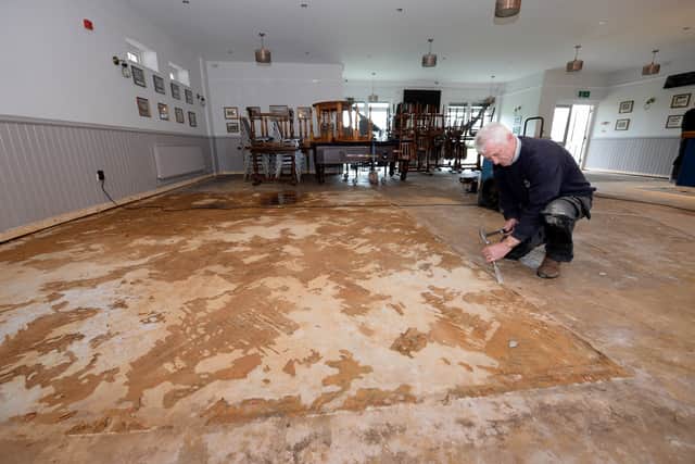 Workman Ian Young scrapes the remnants of the new parquet flooring, which had just been laid
