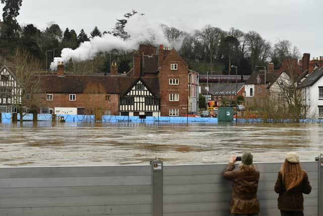 A steam train on the Severn Valley Railway passes through Bewdley with its flood barriers holding back the River Severn