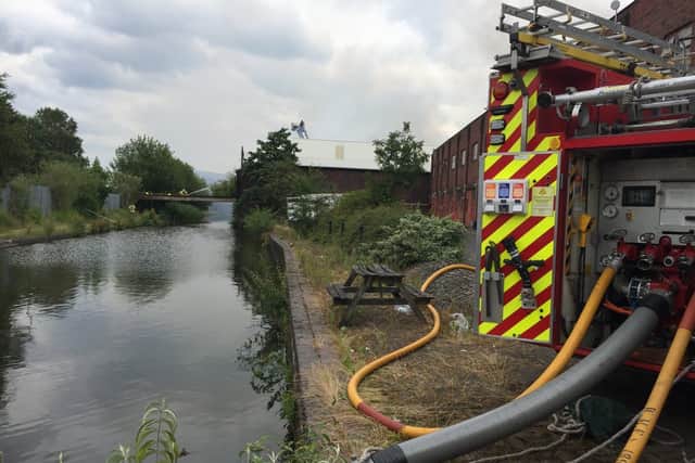 Firefighters pump water from the Engine Arm section of the Birmingham Canal to fight the fire while others assess the building after fears it could collapse into the waterway. Picture: West Midlands Fire Service