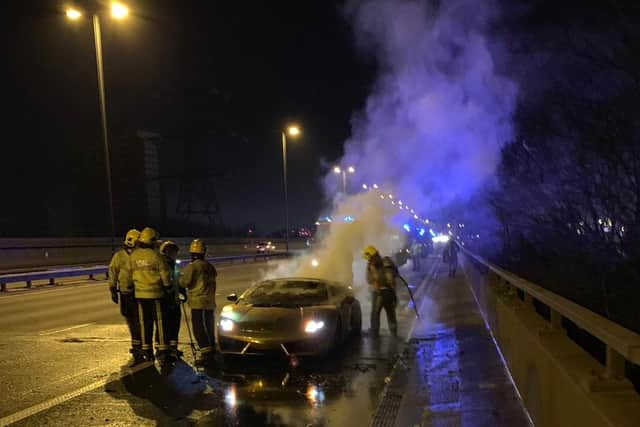 Firefighters attending to the smouldering supercar