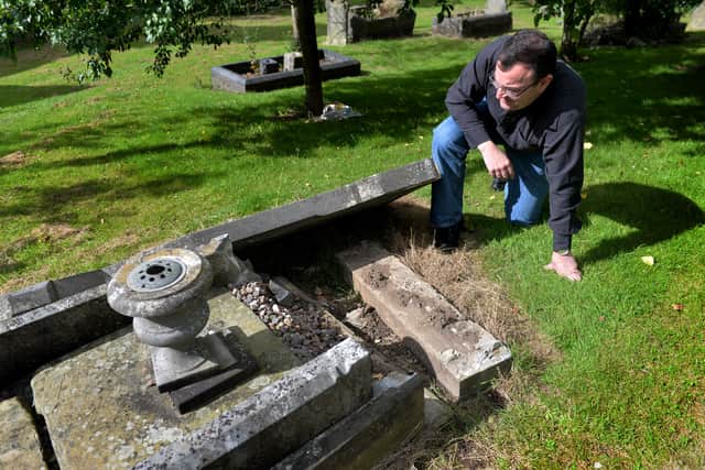 Rev David Hoskin examines the grave