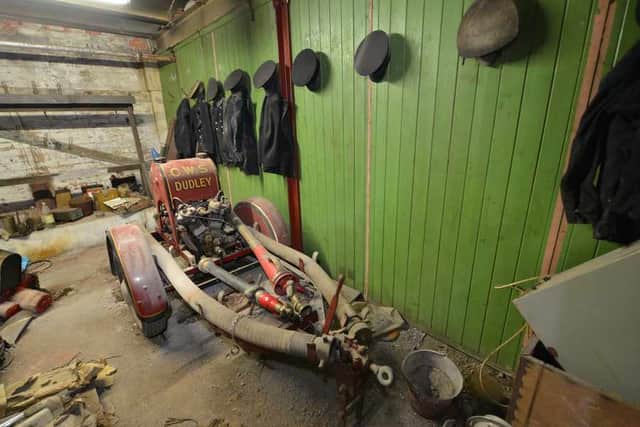 A pump trailer, with 'CWS DUDLEY' lettered in gold on the front, in the fire station which appears not to have changed in 60 years