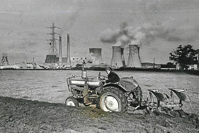 A farmer in his tractor rolls by Rugeley Power station, October 1967