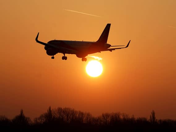 Silhouette of an aeroplane in an orange sky with the sun visible in the background