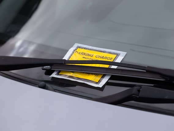 A yellow parking ticket under a windscreen wiper