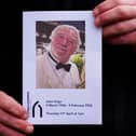 The Order of Service is held up ahead of the memorial service for John Virgo