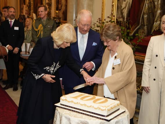 Charles and Camilla cut a cake with 100 year-old Joan Illingworth during a reception at Buckingham Palace