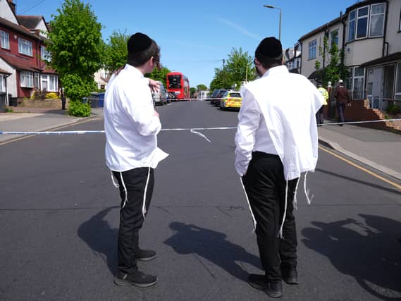 Two men on a road in Golders Green next to police tape