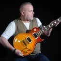 Propstore’s music specialist Mark Hochman holds Slash’s Guns N’ Roses photo-matched tour stage used and autographed Gibson Les Paul ’59 custom shop guitar