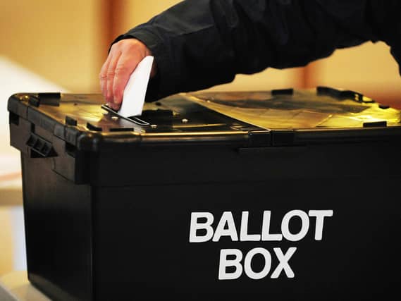 A voter places a ballot paper in the ballot box at the polling station