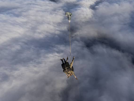 Tandem parachuters upside down, with clouds behind him