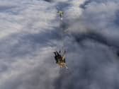 Tandem parachuters upside down, with clouds behind him