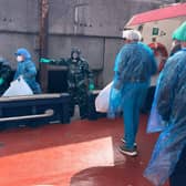 People in protective clothing disembark a boat