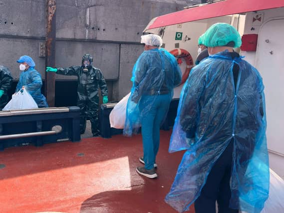 People in protective clothing disembark a boat