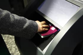 A hand pressing an open passport into a machine to be scanned