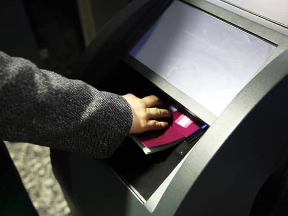 A hand pressing an open passport into a machine to be scanned