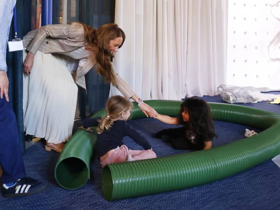 Princess of Wales with children playing in a plastic tube