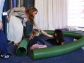 Princess of Wales with children playing in a plastic tube