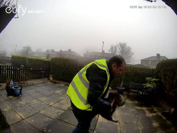 A screengrab from doorbell camera footage showing Catalin Stancu picking cat Nora up