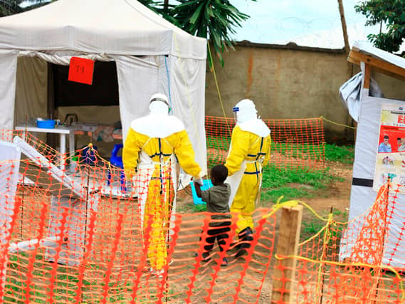 Health workers walk with a boy suspected of having the Ebola virus at an Ebola treatment centre in Beni, eastern Congo
