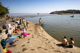 People sitting in the sunshine next to the sea