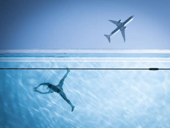 A person swimming in the sky pool in Nine Elms, south London, while a plane rises in the sky