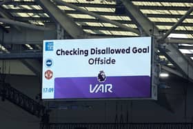 A screen shows a VAR check during a Premier League match at the Amex Stadium